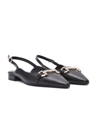Ballerine slingback in pelle nera con punta a punta, caratterizzate da un accento in catena metallica e un tacco basso a blocco. Texture liscia e design minimalista.