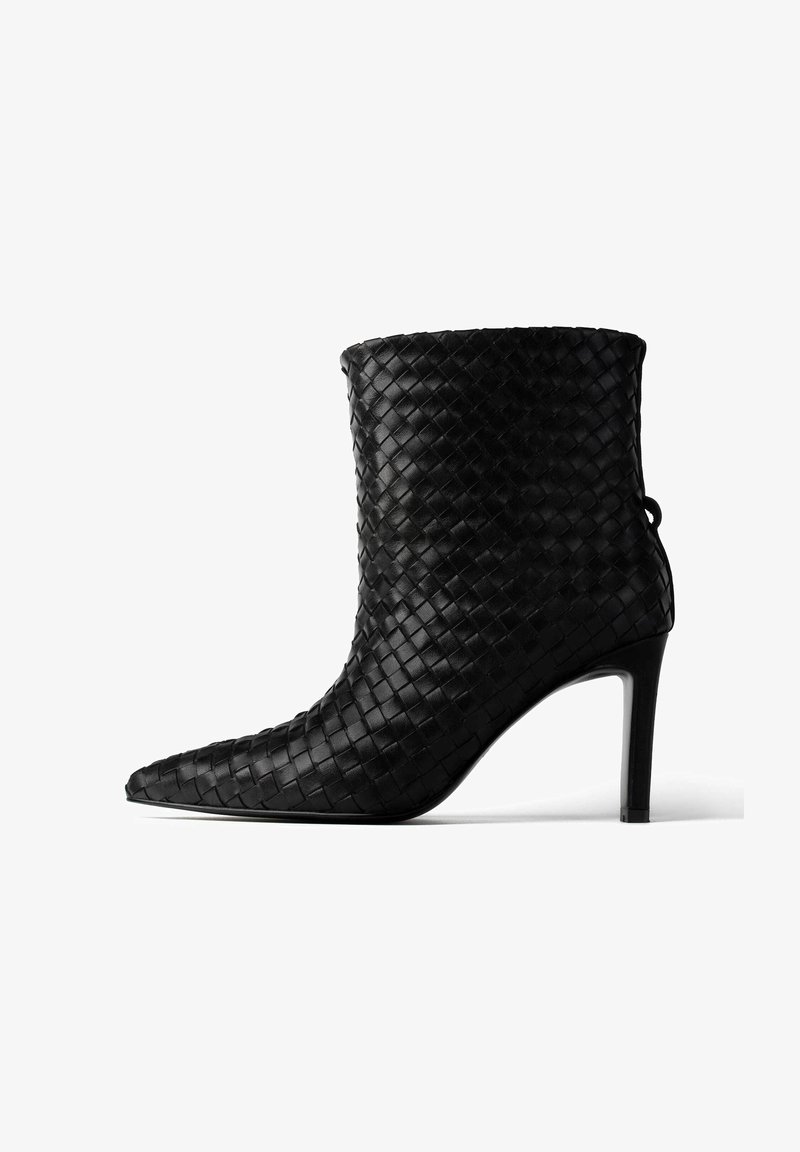 Czarny, pleciony skórzany botek za kostkę z wąskim noskiem i cienkim obcasem w kształcie szpilki. Posiada teksturowaną powierzchnię oraz pętelkę z tyłu.