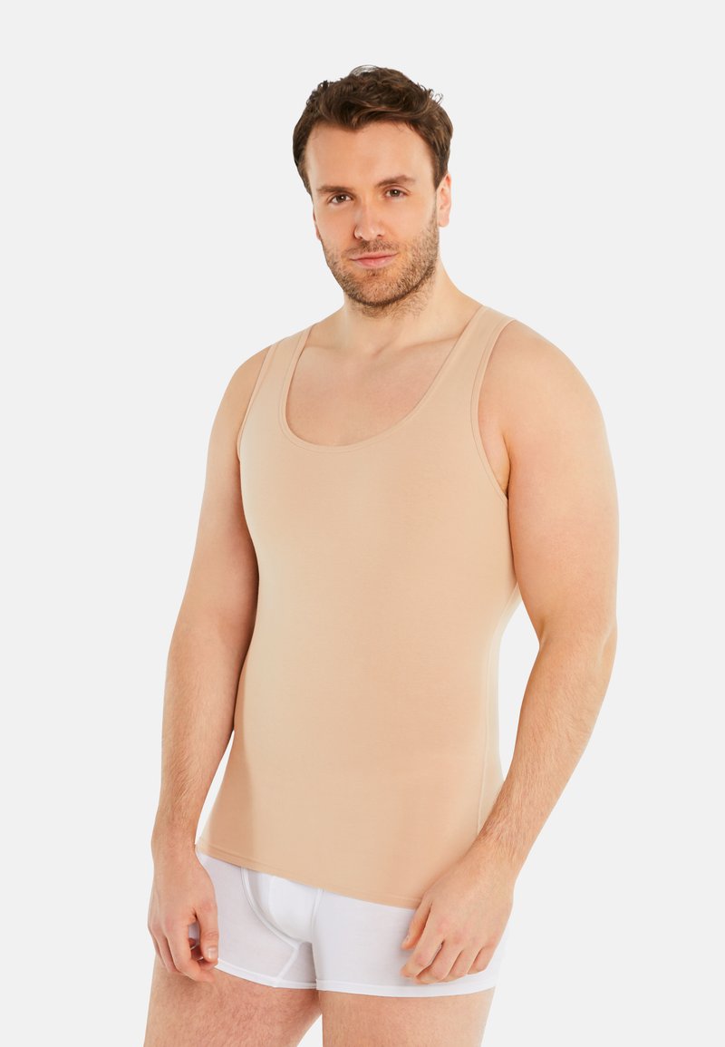 Beige tank top made of stretch fabric, featuring wide straps, a scoop neckline, and a fitted shape. Worn with white boxer shorts.