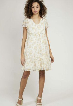 Robe à motif floral en crème clair avec des accents jaunes, décolleté en V, manches courtes et ourlet à volants, fabriquée en tissu léger et fluide.