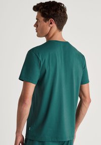 Teal t-shirt gemaakt van zachte katoen, met een ronde hals, korte mouwen en een relaxte pasvorm. Gladde textuur met minimale naden en geen zichtbare logo's.