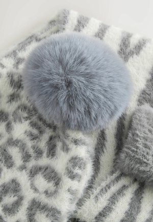 Világosszürke pompon, puha szőrből, fehér és szürke csíkos sál tetején, bolyhos, mintás textúrával.