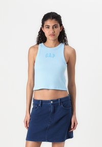 Lyseblå ribbet tanktop med rund hals og GAP-logo, kombinert med en mørk denim miniskjørt med lommer og midje.