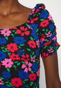 Černý látkový top s barevnými květinovými vzory v růžové, červené a modré barvě. Design zahrnuje nabírané balónové rukávy a čtvercový výstřih.