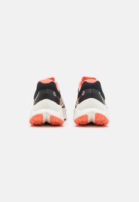 Zapatillas deportivas con un upper negro y rosa, una entresuela blanca y una suela textured naranja. El diseño presenta un tejido de malla transpirable.