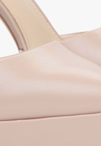 Blush pink handbag made of smooth leather, featuring a structured design, flat handle, and subtle stitching detail along the edges.