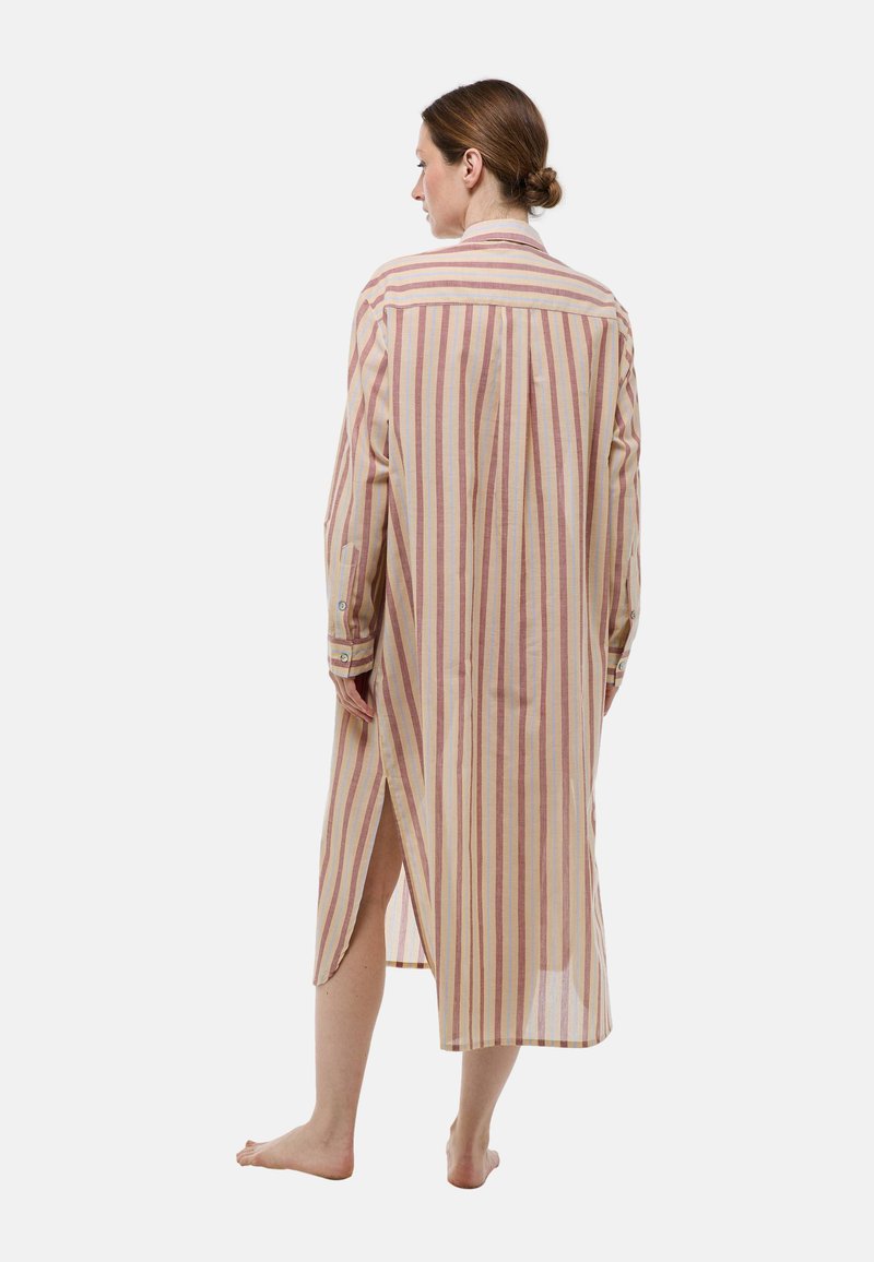 Chemise longue rayée en tissu léger présentant des rayures verticales rouges et beiges, un col boutonné et des fentes latérales pour plus de liberté de mouvement.