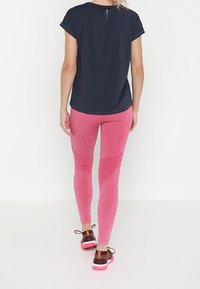 Námořnický sportovní top s krátkým rukávem, spárovaný s růžovými melange legínami. Obuv má hnědý a růžový design s tkaničkami.