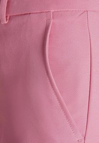 Roze stof close-up van een broek met een gladde textuur, subtiele glans en een zijzak met nette stiksels en een op maat gemaakt ontwerp.