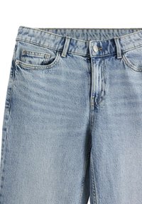 Jeans in denim azzurro chiaro con una texture leggermente sbiadita, cinque tasche e chiusura con bottone metallico in vita.
