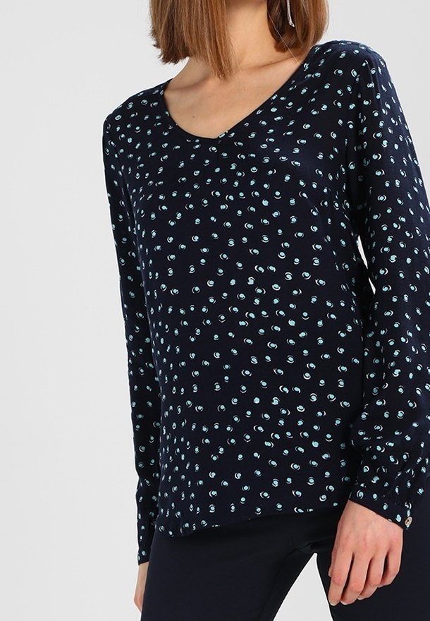 Haut à manches longues marine avec un col en V, présentant un motif de points bleu clair et teal éparpillés. Fabriqué en tissu doux au toucher lisse.