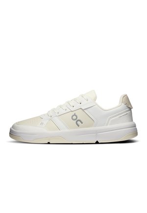Zapatilla blanca de perfil bajo con cierre de cordones, paneles de cuero lisos y perforados, y logo de la marca en el lateral y talón.