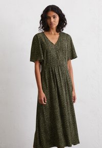 Green midi dress featuring a V-neck, short sleeves, and a subtle floral pattern, made from a lightweight, textured fabric.