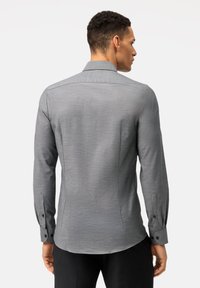 Grau langärmliges Hemd aus dezent strukturiertem Stoff, mit klassischem Kragen und knöpfbaren Manschetten, das eine taillierte Passform und einen Rückenpasse-Design aufweist.