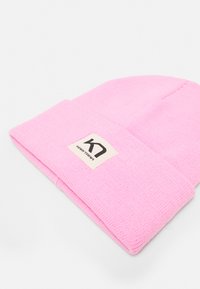 Berretto rosa realizzato in tessuto a maglia con risvolto. Presenta un'etichetta rettangolare con testo nero su sfondo crema.