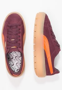 Baskets en daim bordeaux avec des accents orange, dotées d'une semelle texturée et d'une doublure intérieure à motifs, bout rond et lacets plats.