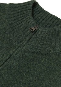 Temnozeleni pleten pulover z visokim rebrastim ovratnikom in zapiranjem na četrt zadrgo. Material se zdi mehak, z obdelavo z teksturo in heather videzom.