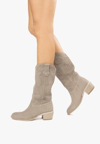 Stivali al ginocchio in suede beige con dettagli cuciti e punta squadrata; tacco a blocco con superficie texturizzata per una migliore aderenza.