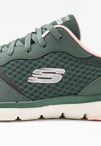 Grön atletisk sko med ett mesh-överdrag, rosa accenter,Texturerade grå paneler, och en vit gummisula med ett mönstrat mönster. Silverfärgad logotypdetalj.