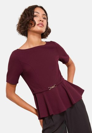 Vinatift peplum-topp med korta ärmar, med en åtsittande midja som betonas av en silverfärgad spänne. Slät tygtextur, strukturerad design.