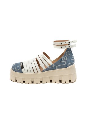 Massieve platformsandaal met witte leren bandjes, dubbele enkelgesp, blauwe denimhak en dikke beige zool met diepe profielzolen, zijaanzicht.
