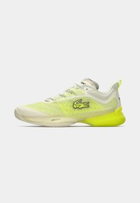 Lacoste sporta kurpes gaiši pelēkā un neona dzeltenā krāsā. Tām ir acs materiāla augšdaļa, padosies ar mīkstu zoli un izteikts Lacoste krokodila emblēma sānos.