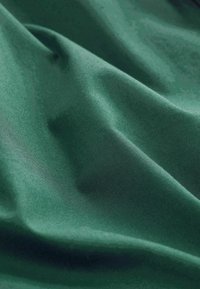 Teren verde cu o textură netedă, ușor lucioasă, prezintă pliuri moi și un model de țesătură consistent pe întreaga suprafață.