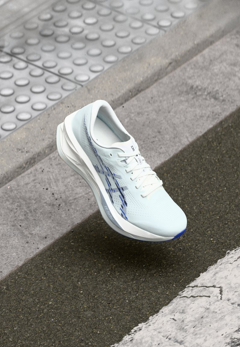 Chaussure de course bleu clair avec une tige en mesh respirant, des accents blancs et une semelle amortie. Présente un motif décoratif sur le côté.