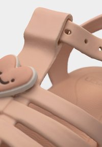 Ελαφρώς ροζ παιδικό σανδάλι με ρυθμιζόμενο λουράκι και διακόσμηση σε σχήμα καρδιάς που χαμογελά στη μπροστινή πλευρά.