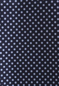 Tissu bleu marine avec un motif de petits points circulaires bleu clair et blanc régulièrement espacés.