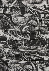 Tecido preto e branco com um padrão marmoreado em espiral, apresentando uma superfície ligeiramente texturizada e secções franzidas.