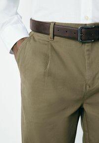 Khaki trousers with a smooth texture, featuring side pockets, and a brown leather belt with a rectangular metal buckle.