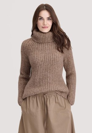 Brauner gerippter Pullover mit hohem, umgeschlagenem Rollkragen, kombiniert mit einem beigen Rock mit Zugband, der eine weiche, strukturierte Optik aufweist.