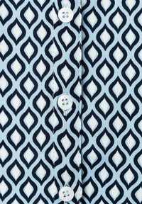 Light blue fabric with a navy and white diamond pattern. Features a button placket with round white buttons and a textured weave.