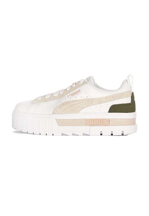 Białe sneakersy z beżowymi akcentami, teksturowanym materiałem, płaskim sznurowadłem i grubą podeszwą. Zawierają zielony panel z tyłu oraz logo z boku.