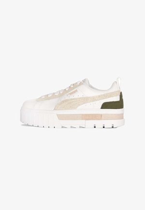 Białe sneakersy z beżowymi akcentami, teksturowanym materiałem, płaskim sznurowadłem i grubą podeszwą. Zawierają zielony panel z tyłu oraz logo z boku.