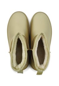 Tan enkellaarzen met een gladde synthetische buitenkant, gevoerd met nep-bont en met gestikte details langs de kraag en hak.