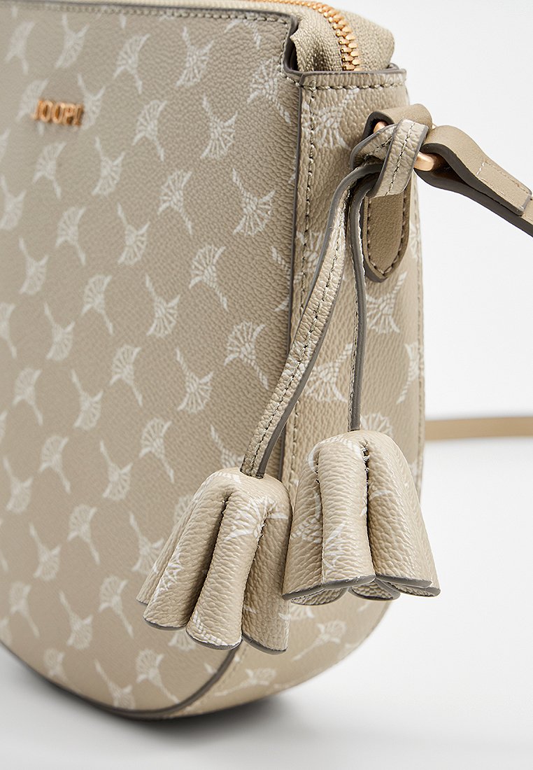Beige Tasche aus Kunstleder mit geometrischem Muster, ausgestattet mit einem Reißverschluss und dekorativen Quasten am Tragegurt.