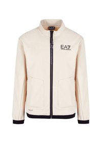 Giacca beige con zip e colletto alto, zip nere, due tasche frontali e logo EA7 sul petto. Tessuto liscio e leggero.