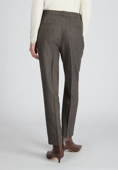 Aangepaste bruine broek van een gestructureerde stof, met een rechte pijp ontwerp, twee achterzakken en gedragen met bruine leren kuitenlaarzen met hak.