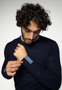 Pulover bleumarin confecționat dintr-un material moale, cu accente contrastante de bleu deschis la manșete și un detaliu subtil al logo-ului pe mânecă.