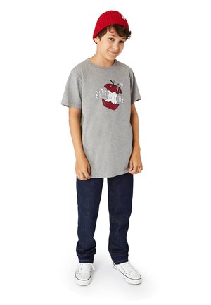 Graues Baumwoll-T-Shirt mit einem roten Apfel-Design und dem Text "BITE ME", getragen mit dunkelblauen Jeans und weißen Sneakers, abgerundet mit einer roten Strickmütze.