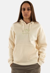 Crème-kleurige hoodie van zachte stof, voorzien van een kangoeroezak en koorden. Het heeft een groen hart- en wereldlogo op de borst.