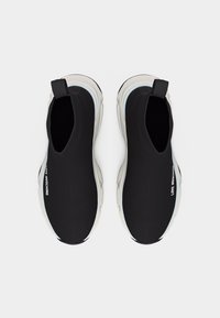 Ζευγάρι μαύρα sneakers χωρίς κορδόνια με λευκές σόλες και λουράκια έλξης, με το κείμενο "LOVE MOSCHINO" στα πάνω πλαϊνά μέρη.