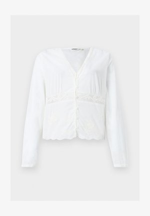 Fehér, hosszú ujjú, gombos blúz V-nyakkivágással, csipkés részletekkel a derék körül és fodros szegéllyel.