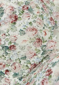 Bloemenkant stof met een witte basis en een mix van rode en blauwe bloemen, groene bladeren en een open geweven textuur overal.