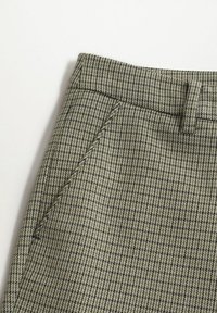 Pantalon taille haute avec petit motif à carreaux verts et noirs, poche avant inclinée et passants pour ceinture sur fond blanc.