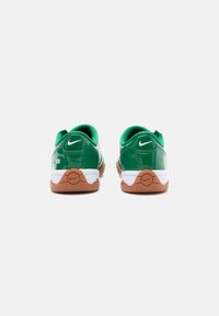 Zaļas patentētas ādas kurpes ar baltu vidusdaļu un brūnu gumijas zoli. Nike logo baltā krāsā uz papēža. Apaļa forma ar mīkstinātu apkaklīti.