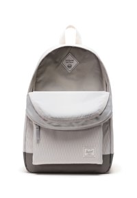 Sac à dos gris clair en tissu à motif losange, avec une poche avant et une base gris foncé contrastante. Il dispose d'une poignée supérieure et d'une étiquette intérieure.