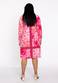 Kurzärmliges pinkes Kleid mit floralen Mustern; entworfen mit einem rechteckigen Raster, präsentiert lebhaftes Pink und Orange sowie eine lockere Silhouette.